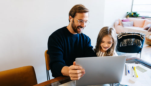 Father showing his daughter something on a laptop