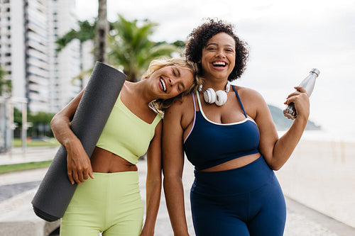 Portrait of happy fitness buddies standing on the beach promenade, ready for a workout