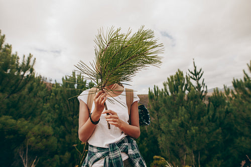 Woman traveller holding a branch of a tree covering her face