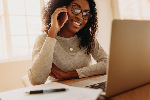Businesswoman working from home on laptop and mobile phone