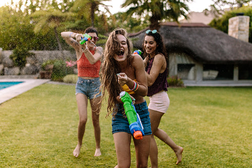 Female friends doing water gun battle