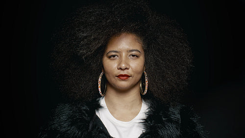 Woman with afro hairstyle smiling on black background