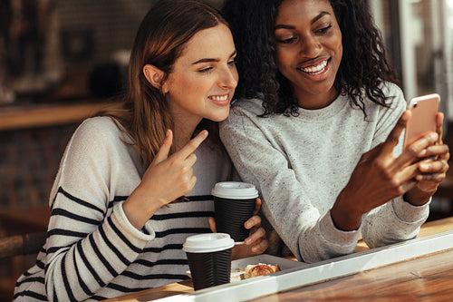 Friends sitting in a cafe looking at mobile phone