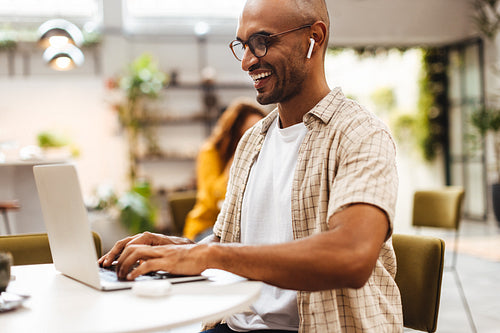 Male freelancer typing on his laptop in a coffee shop