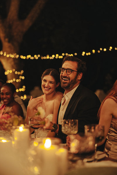 Happy couple celebrating joyous wedding reception with guests under twinkling lights