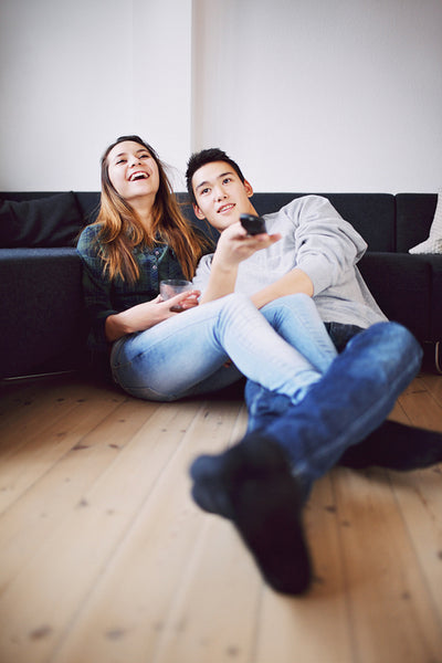 Teenage couple watching comedy show on TV