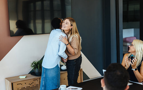 Employees sharing a heartfelt moment during a team meeting in a modern office