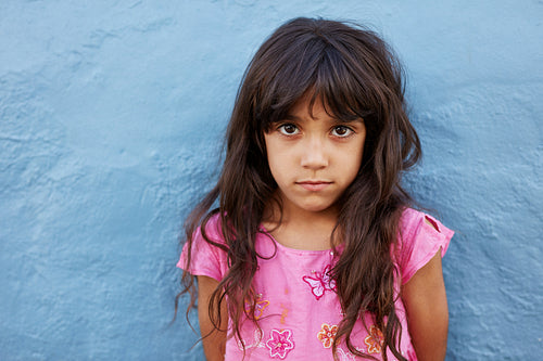 Innocent little girl standing against blue wall