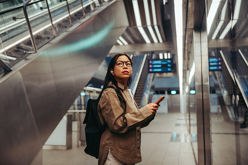 Commuter at station checking phone during travel