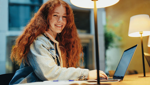 Female student sitting in library with her laptop