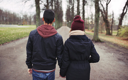 Teenage couple walking in park holding hands