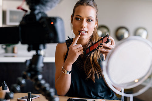 Young female vlogger recording a make-up video for her vlog.