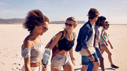 Group of young friends walking down a beach