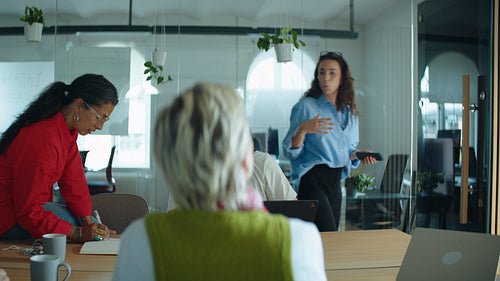 Coworkers listen as woman leads a business meeting in a bright office