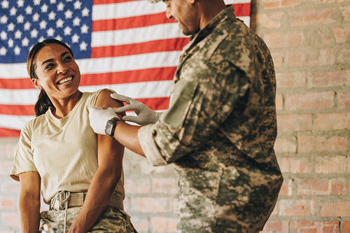 Carefree servicewoman smiling at the military nurse after vaccin