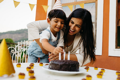 Mother and son placing candles on a birthday cake during celebration