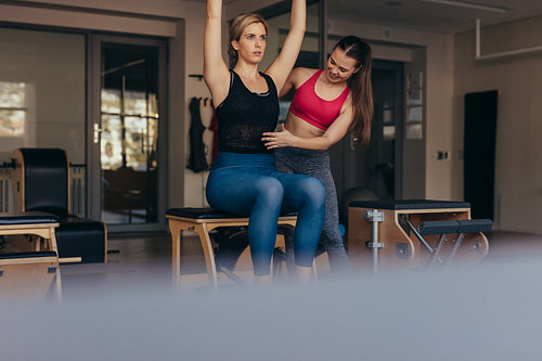 Pilates trainer instructing woman at the gym