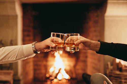 Two hands toasting with whiskey glasses