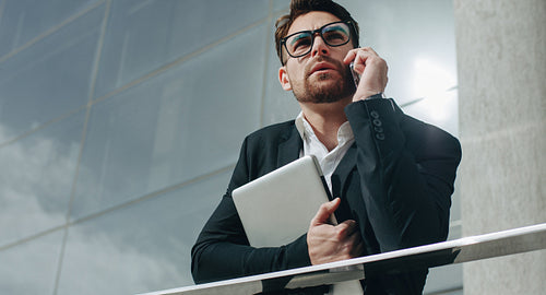 Business person holding a laptop talking on cell phone
