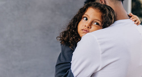 Cute little girl embracing her father's arms