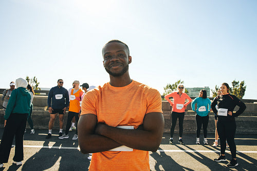 Confident African male runner at a marathon event with diverse group