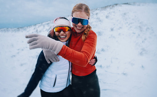 Two women embrace after winter training in snowy landscape