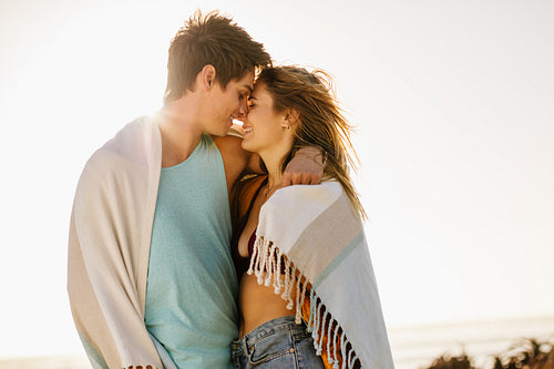 Close up of romantic couple at the beach with a towel wrapped around them