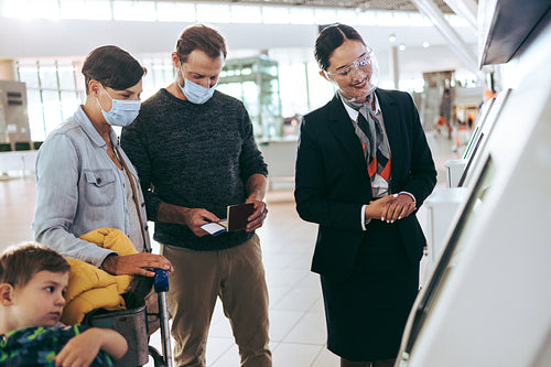 Airport staff helping family at self check-in machine