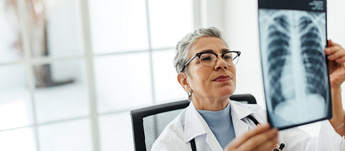 Examining an x-ray image, female radiologist making a diagnosis in her office