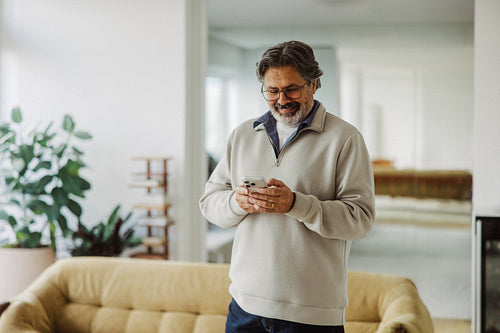 Senior man uses smartphone at home in retirement