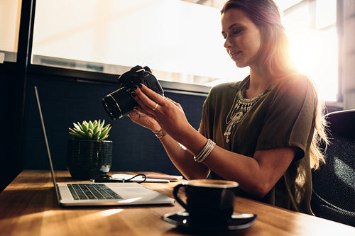 Young female vlogger watching her camera while editing her vlog on computer.
