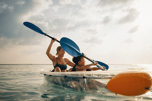 Mother and son paddling a canoe together on a holiday in a calm sea