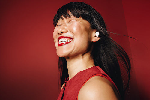 Joyful woman with earbuds in studio portrait enjoying music