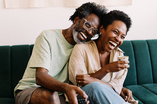 Happy couple having fun watching tv together at home
