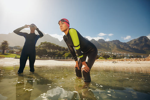 Determined athletes in wet suits preparing for triathlon