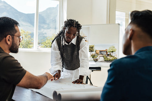 Team of architects discussing project blueprints in an office with natural light