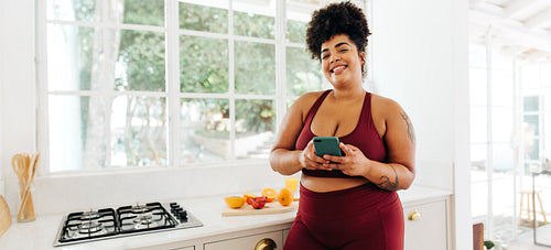 Fitness woman using cell phone in kitchen