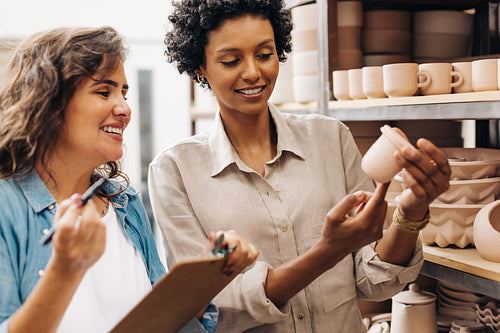 Happy female ceramists discussing on of their earthenware products