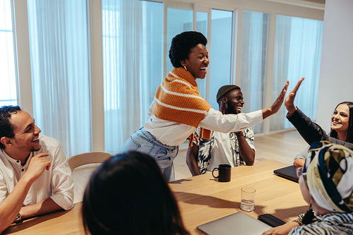 African businesswoman gives a high-five to colleagues during a successful meeting