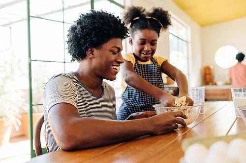 Young Brazilian girl kneading a cake dough with her hands in a mixing bowl