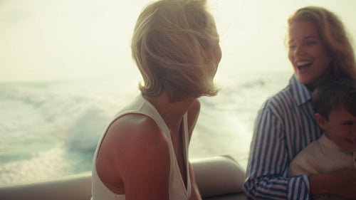 Mother and daughter with child laughing on a beautiful sunlit boat cruise