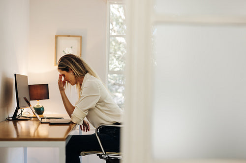 Businesswoman feeling overwhelmed in her office