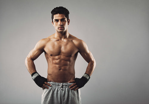 Strong young male boxer on grey background