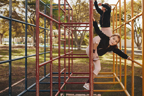 Little girls enjoying climbing on metal structure at playground