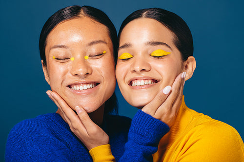 Best friends in beauty: Two young women smile and embrace each other with makeup on