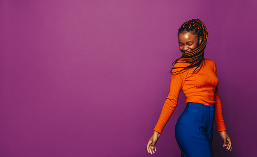 Smiling girl with vibrant two-tone braids celebrating on a colourful background