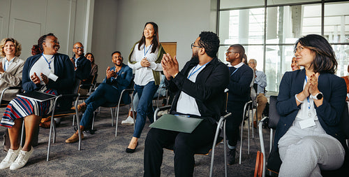 Professional speaker entering stage at business conference with audience clapping