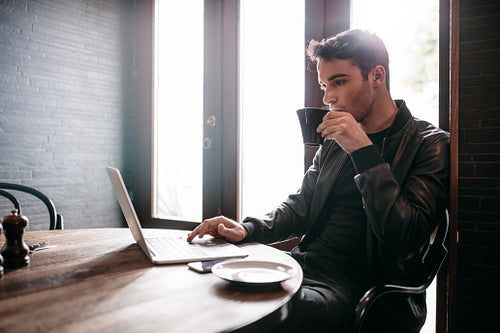 Young man using laptop at cafe