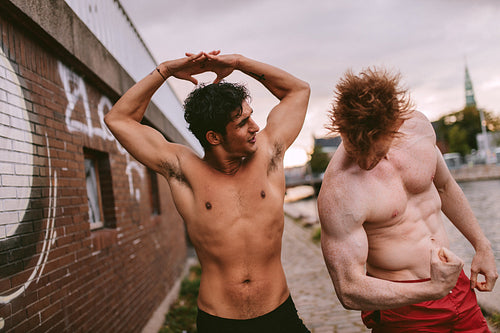Two young men flexing their muscles outdoors