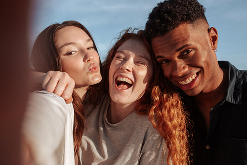 Cheerful friends taking a group selfie outdoors